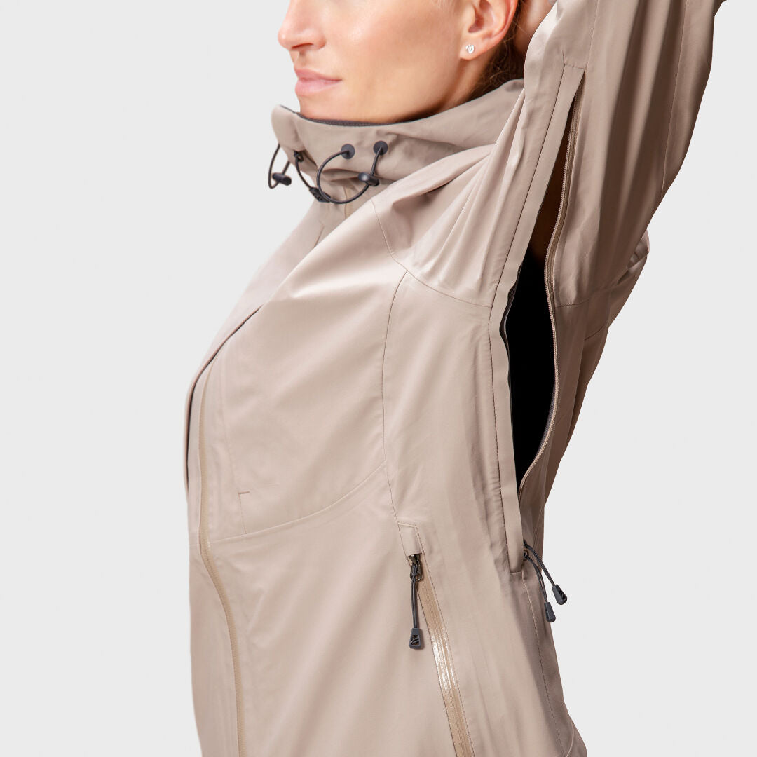 Woman in Halti Kaarna DX 3L Shell Jacket, beige, raising her left arm with underarm vent unzipped.