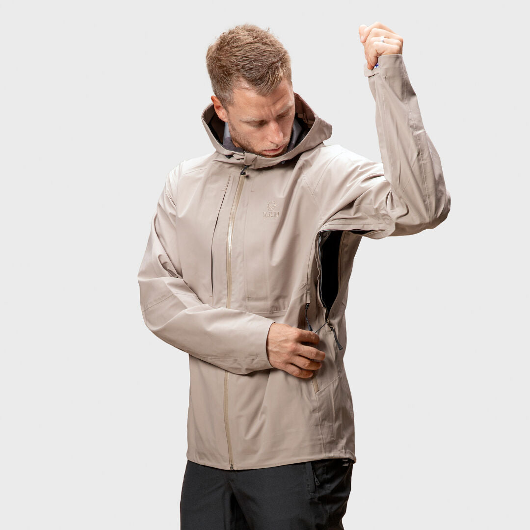 A man wears the Halti Kaarna Mens DX 3L Shell Jacket, unzipping the side vent, ideal for outdoor activities.