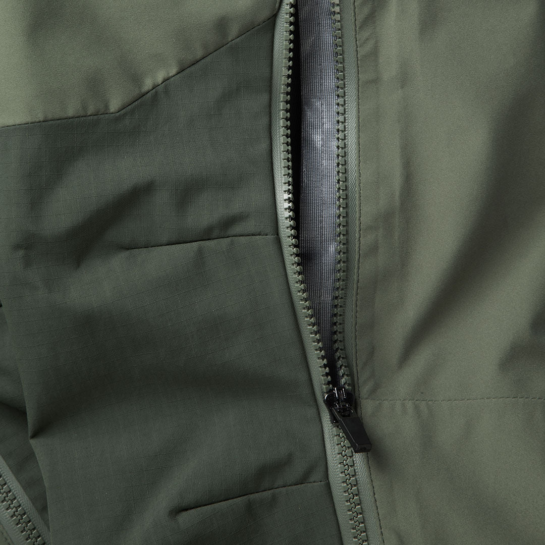 Close-up of a green jacket with pocket stitching, next to Halti Hiker DrymaxX 3L Ventilated Pants Womens.