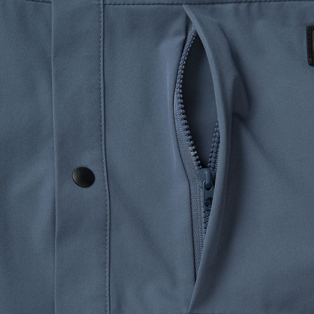 Close-up of Haltis Bluusi Unisex Shirt in blue, shown with a breathable fabric, zip pocket, and black snap button.