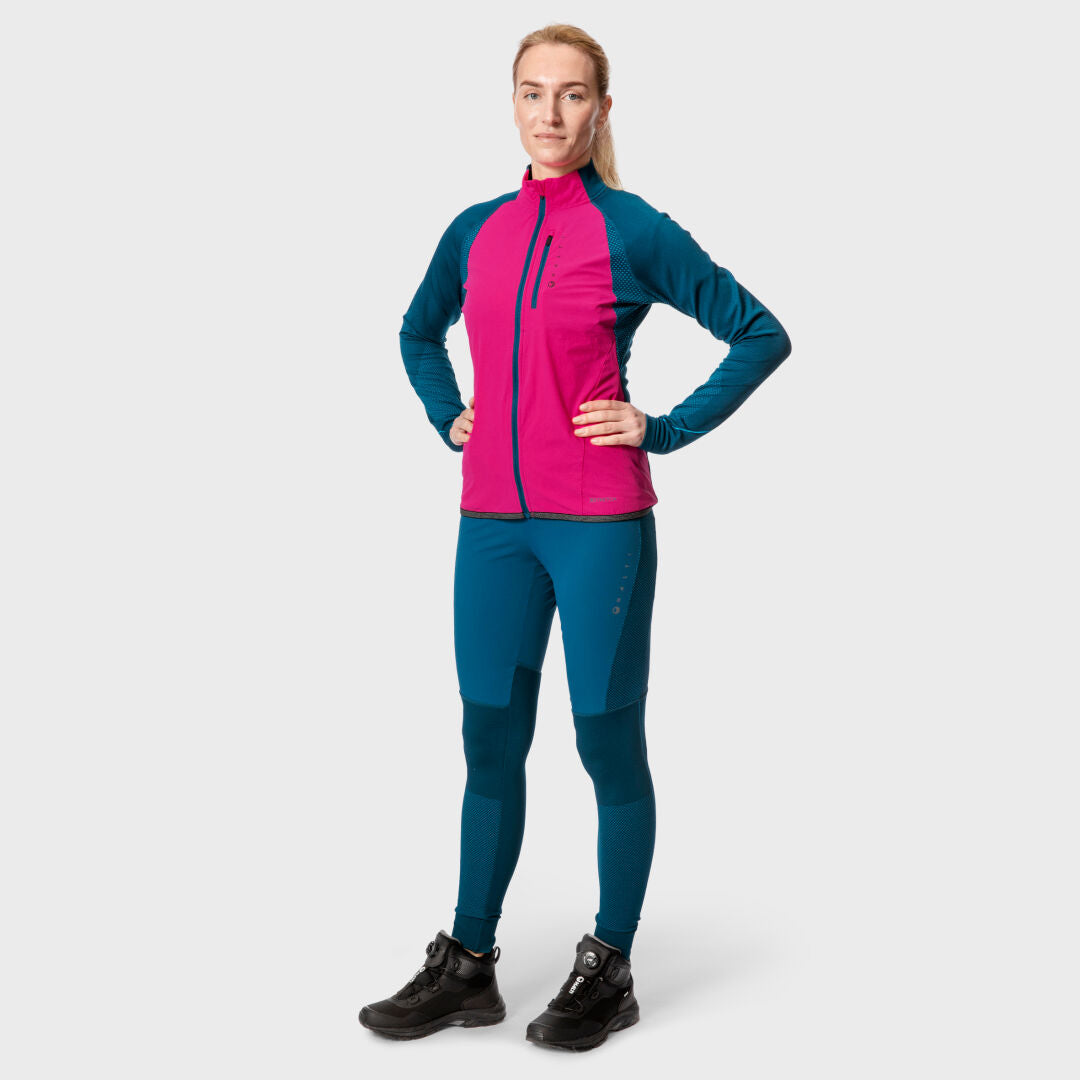 A woman stands forward in Halti Tracks Womens Seamless Tights and an athletic jacket with breathable, weather-resistant fabric.