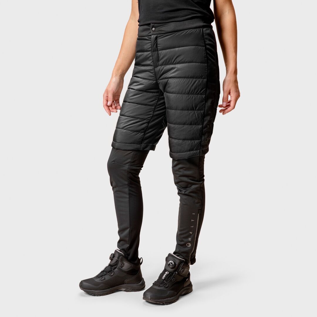 Model wears Halti Hanki Warm Hybrid Shorts for women over leggings and boots, set against a light gray background.