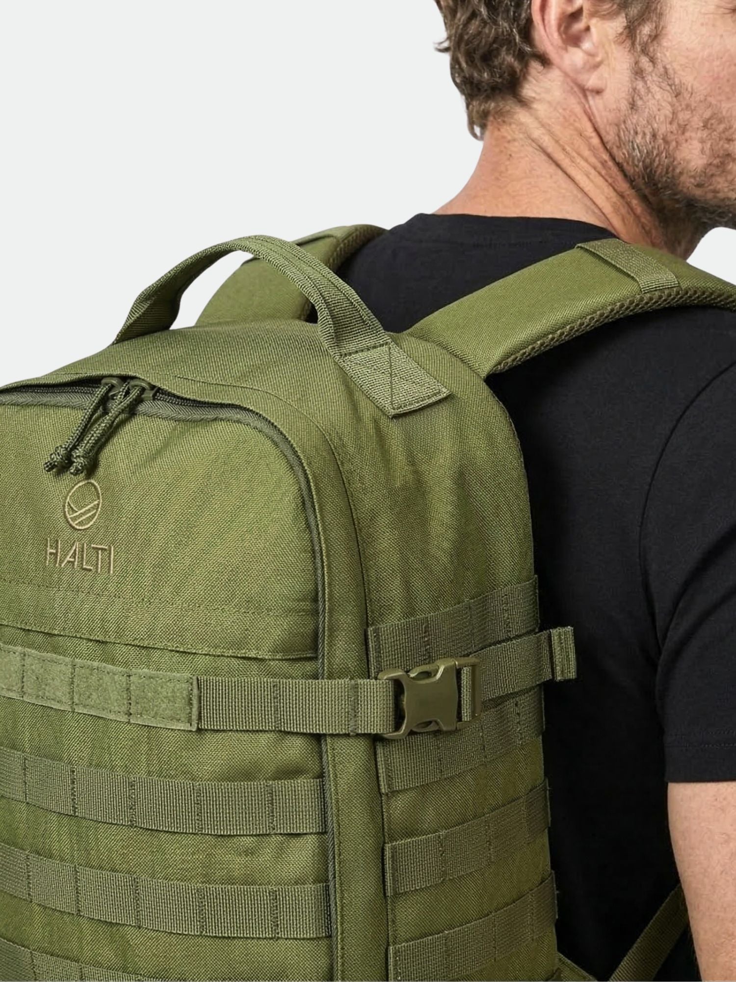 A person in a black shirt carries an olive green Halti Sandstorm 1 Backpack with a side buckle for hunting.