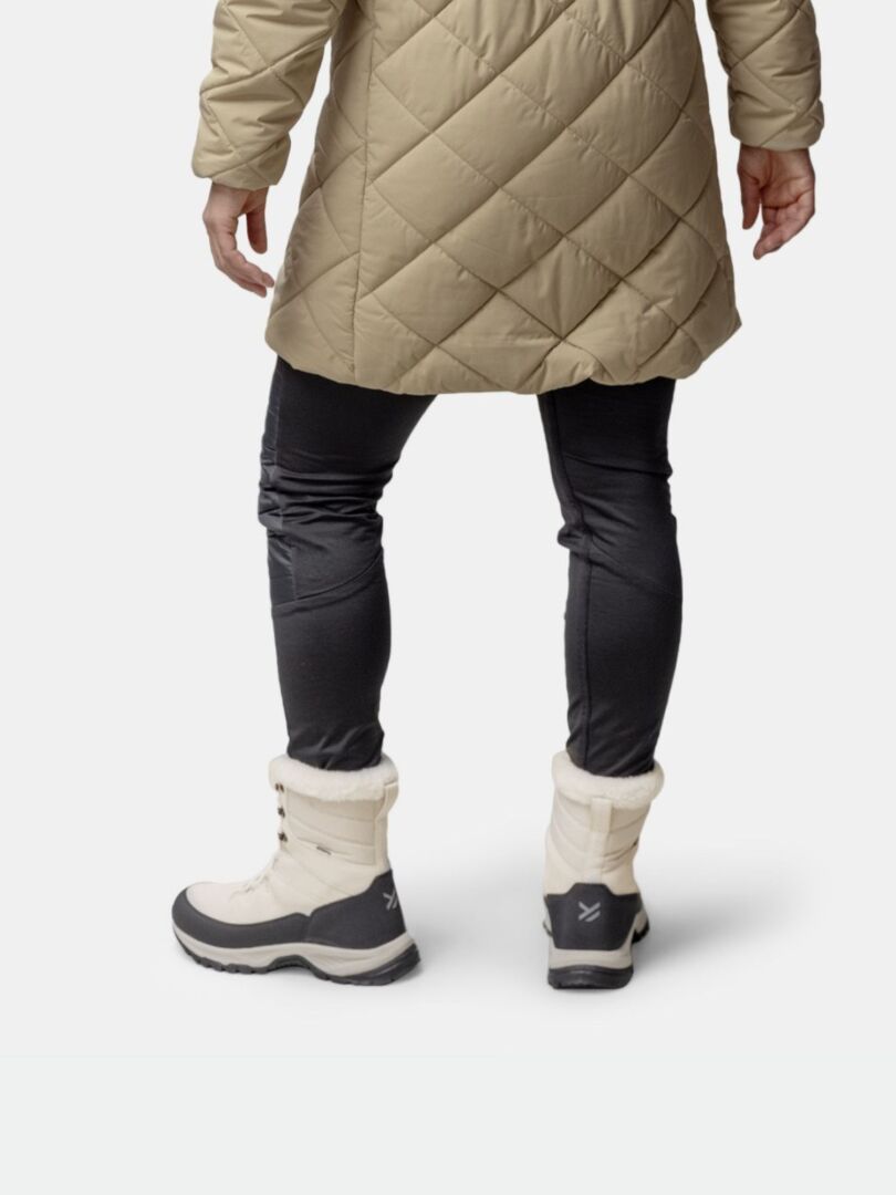 A person in a tan quilted coat, black pants, and Halti Tornio 2 DX Winterboot is shown from the back.