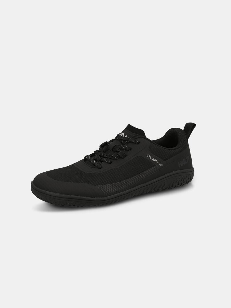 The Halti Tuntuma Barefoot Shoe is black with a textured sole, lace-up front, and branding, shown on a white background.