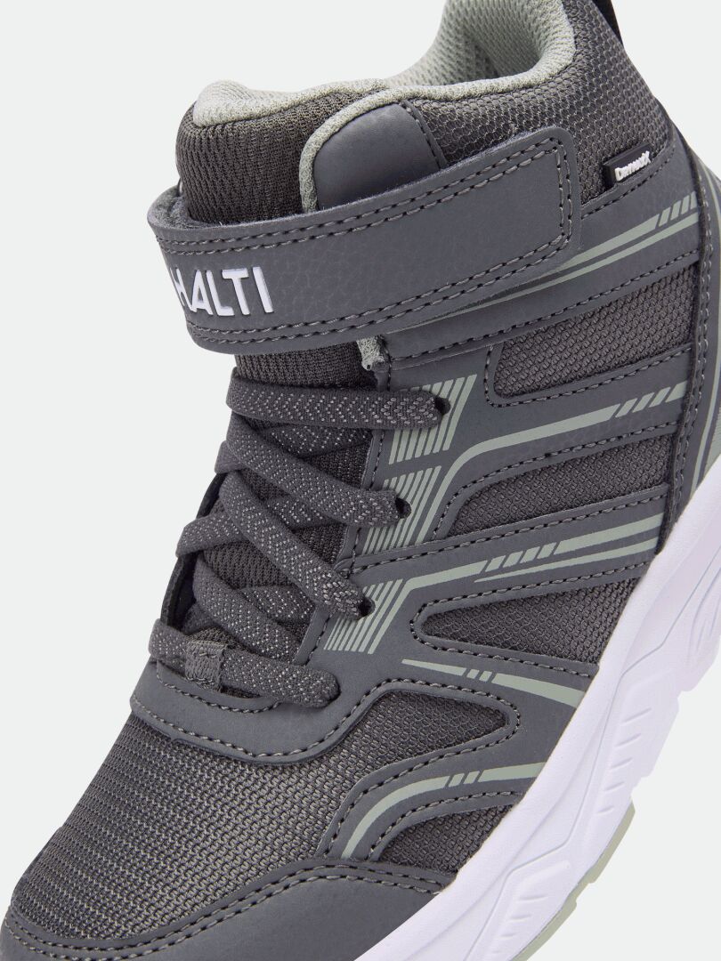 Close-up of gray Zuma Mid DX Sneaker for kids by Halti with laces, Velcro strap, and Halti branding on the strap.
