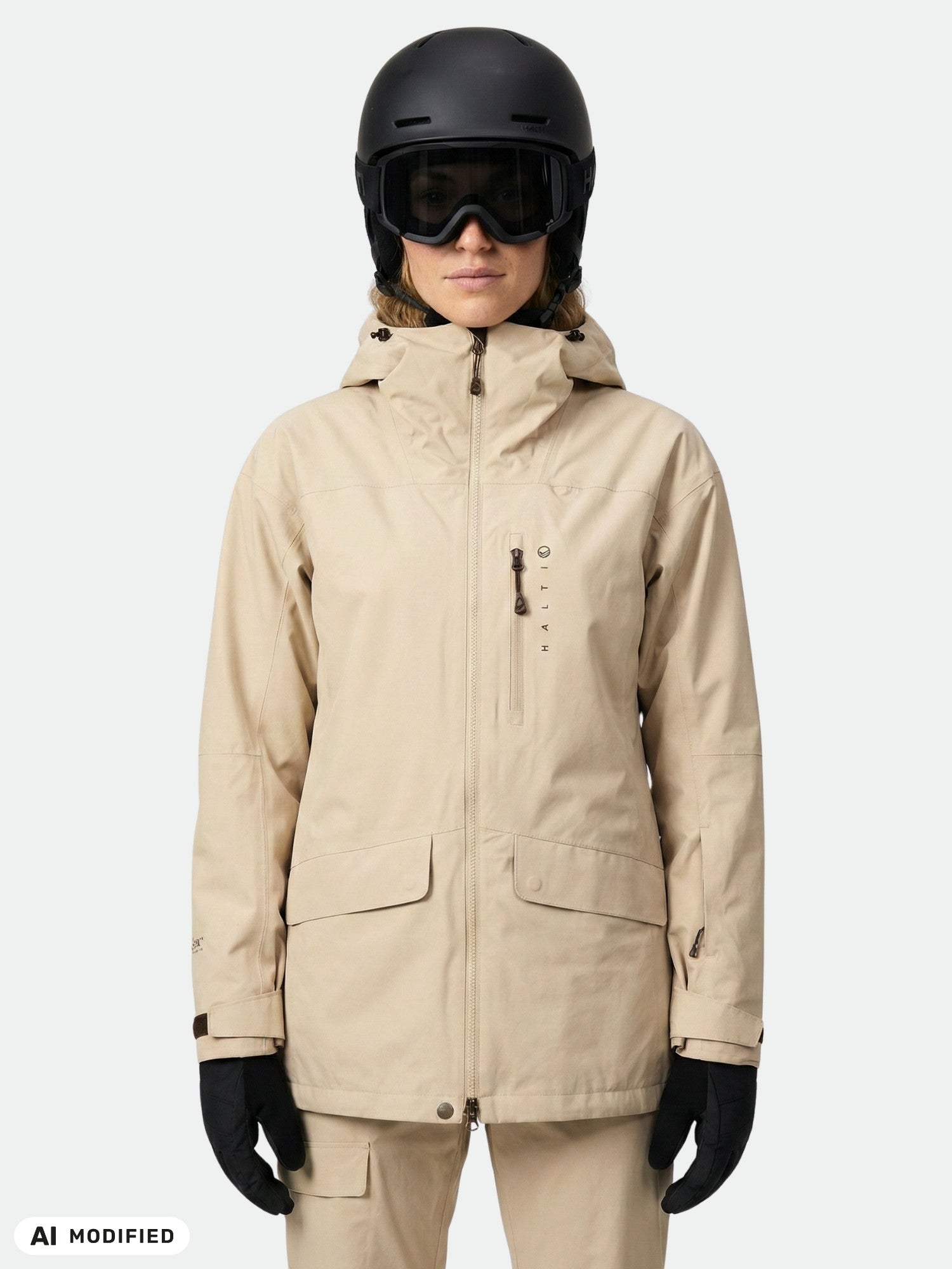 Person in a beige Halti Settler 3L DX Ski Jacket, beige pants, gloves, helmet, and goggles against a plain background.