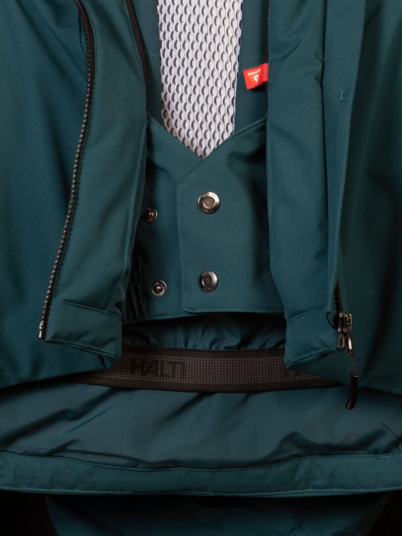Close-up of a dark teal Halti Vertica DX Ski Jacket Men’s featuring an internal snow skirt and a buttoned front placket.