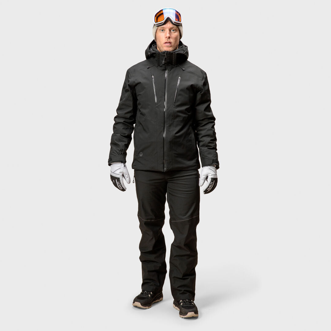 Man in Halti Vertica DX Ski Jacket, black winter pants, white gloves, black shoes, and ski goggles on head.