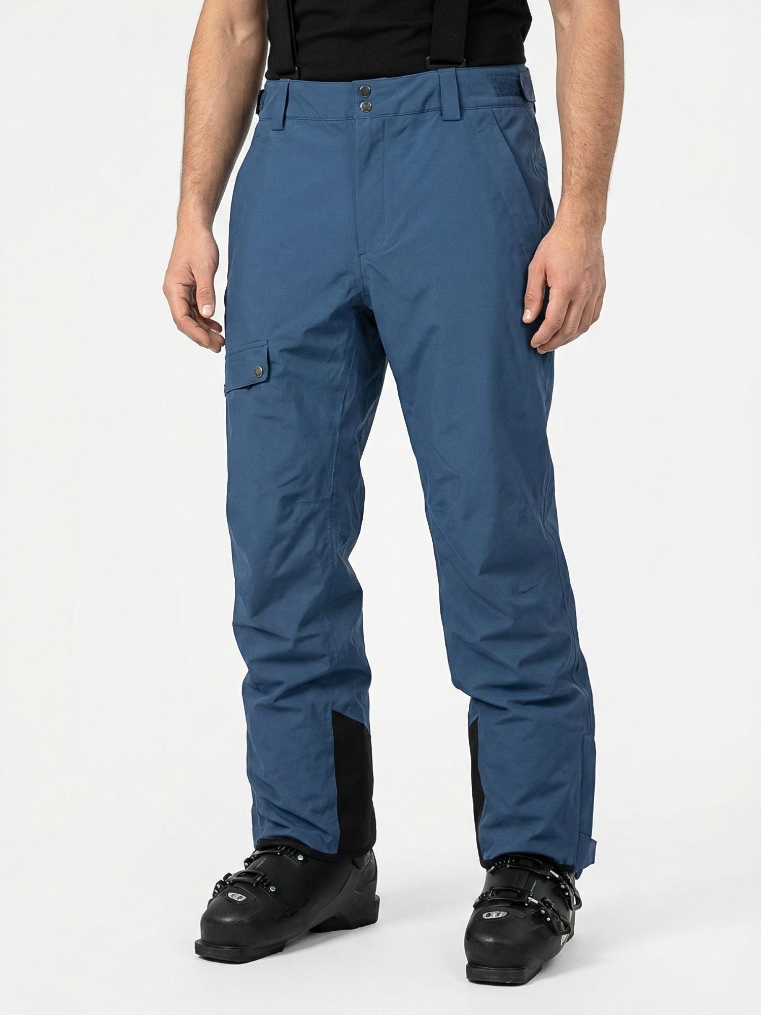 A man wears Halti Settler 3L DX Ski Pants in blue with black boots and shirt, standing against a white background.