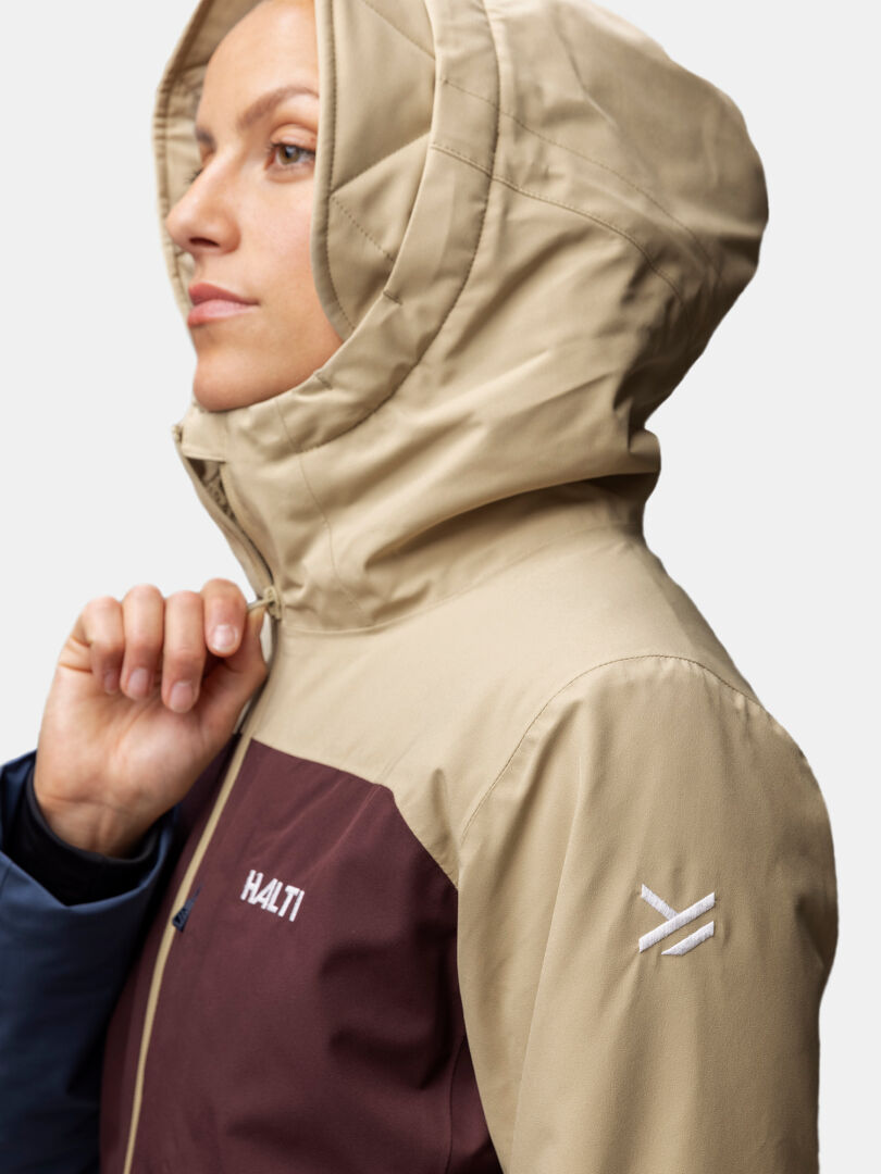 Woman in a beige and maroon Halti Gracer DX Ski Jacket, shown in side profile against a plain background.