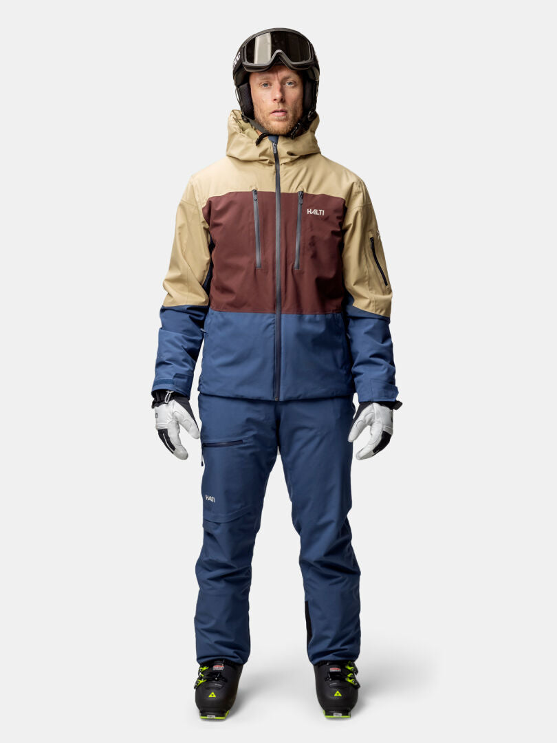 A man in a Halti Melvik Dx Ski Jacket stands facing forward, wearing ski goggles and gloves.