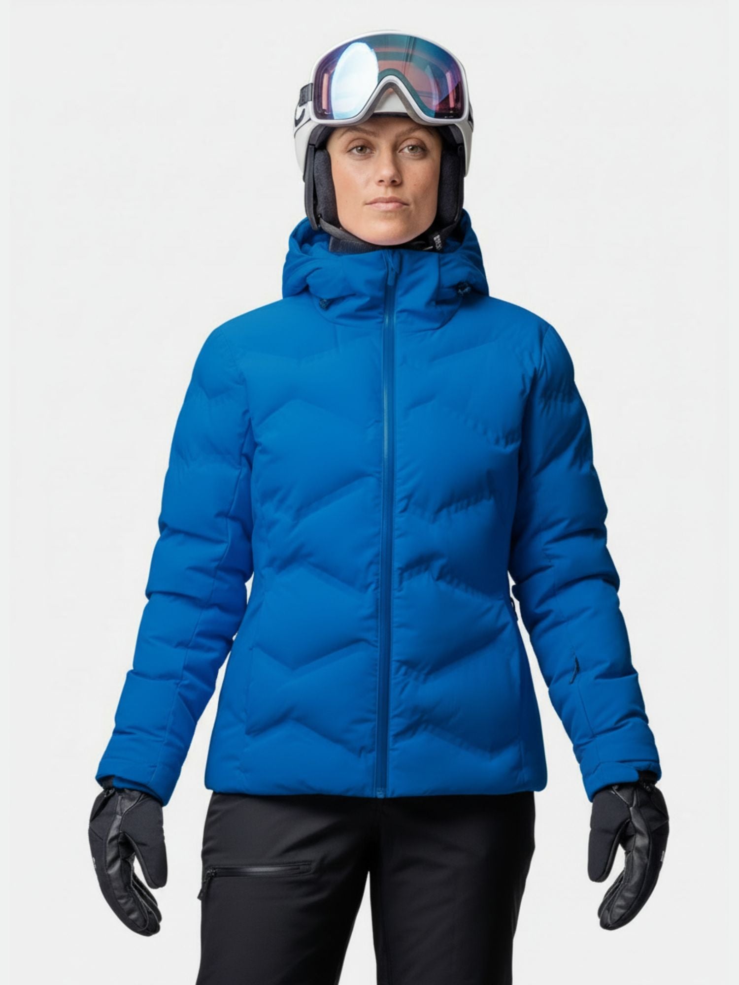 A woman in a Halti Nordic Arcty II Ski Jacket stands facing forward in black pants, helmet, goggles, and gloves.