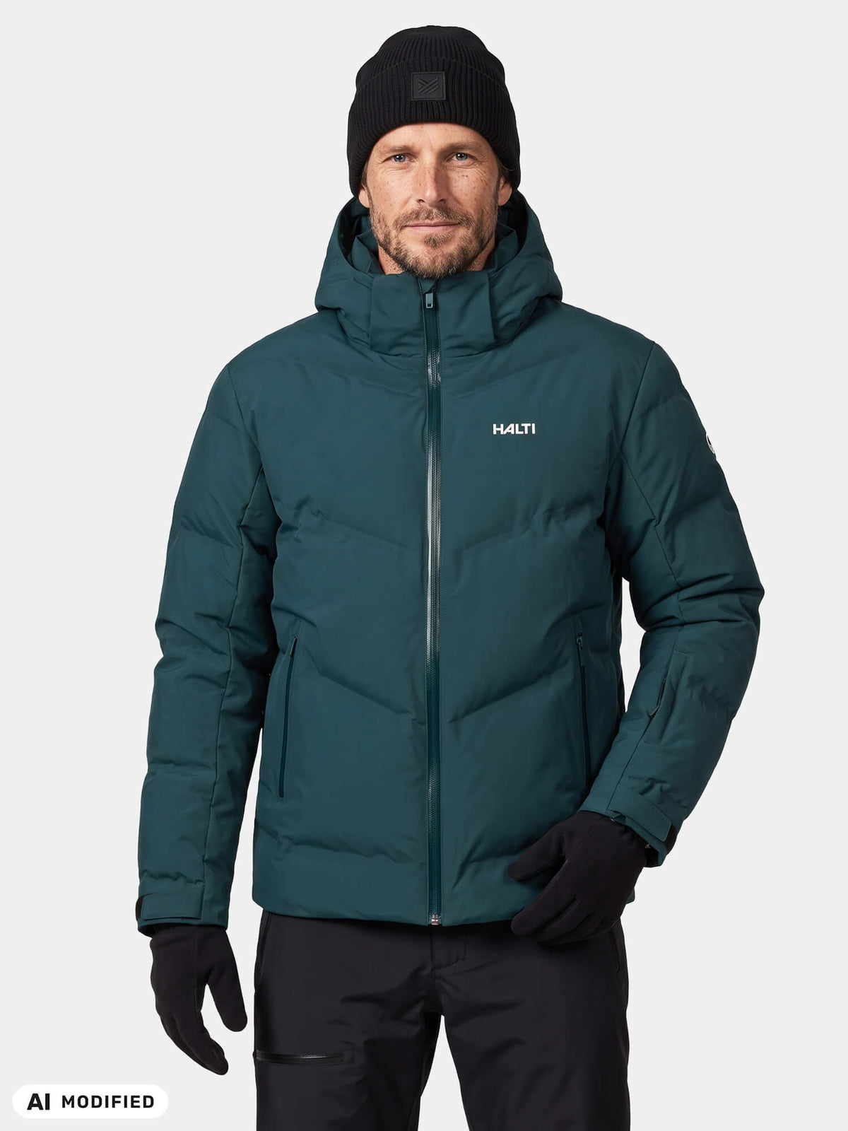 A man wearing a teal Halti Nordic Arcty II Ski Jacket, a black beanie, and black gloves.