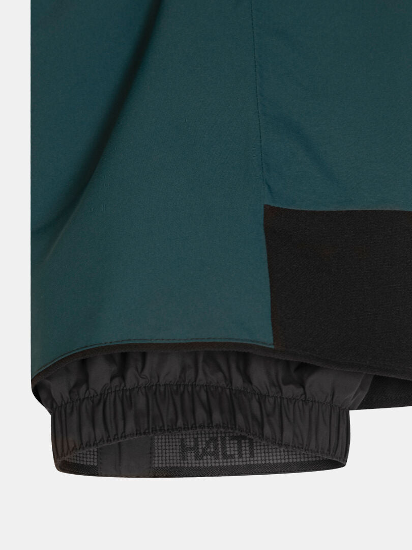Close-up of a Carvey II DX Ski Pants Women’s leg in dark teal with a black elastic snow gaiter at the hem.