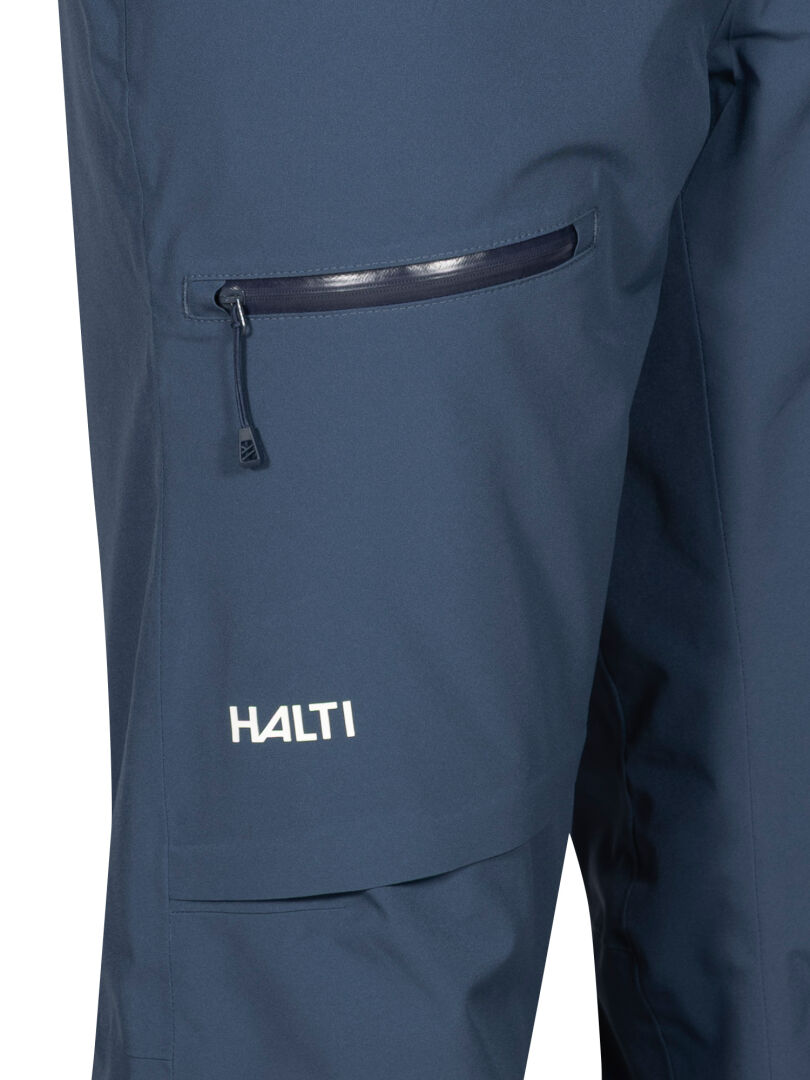 Close-up of Halti Carvey II DX Men's blue waterproof ski pants with zip pocket and white logo above the knee.