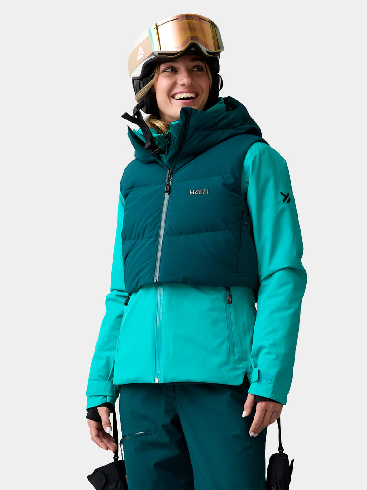 A smiling woman wearing a Halti Varion 2in1 DX Ski Jacket, helmet, and goggles.