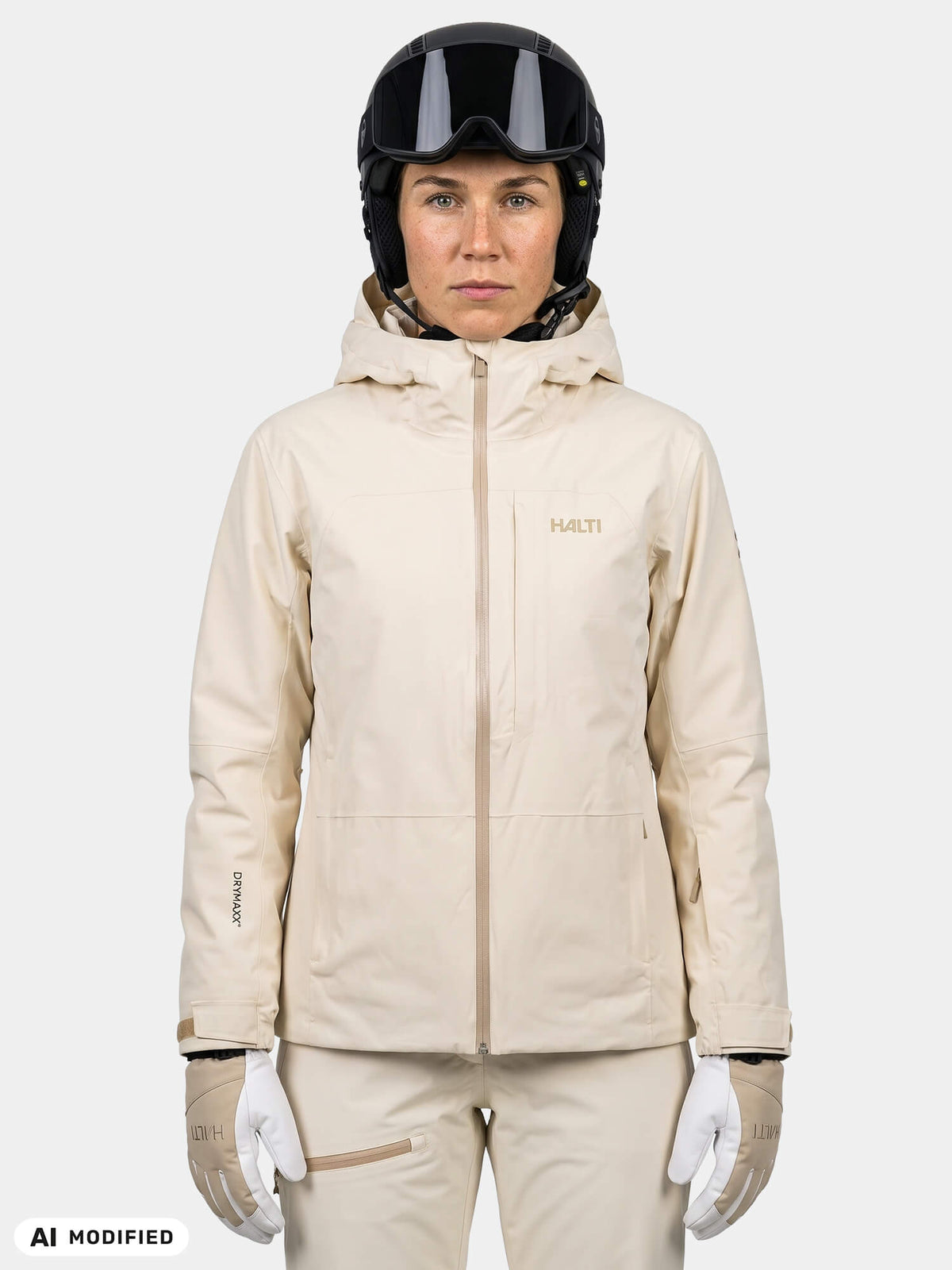 A person wearing a cream-colored Halti Melvik DX Ski Jacket Women’s, black helmet with goggles, and white gloves.
