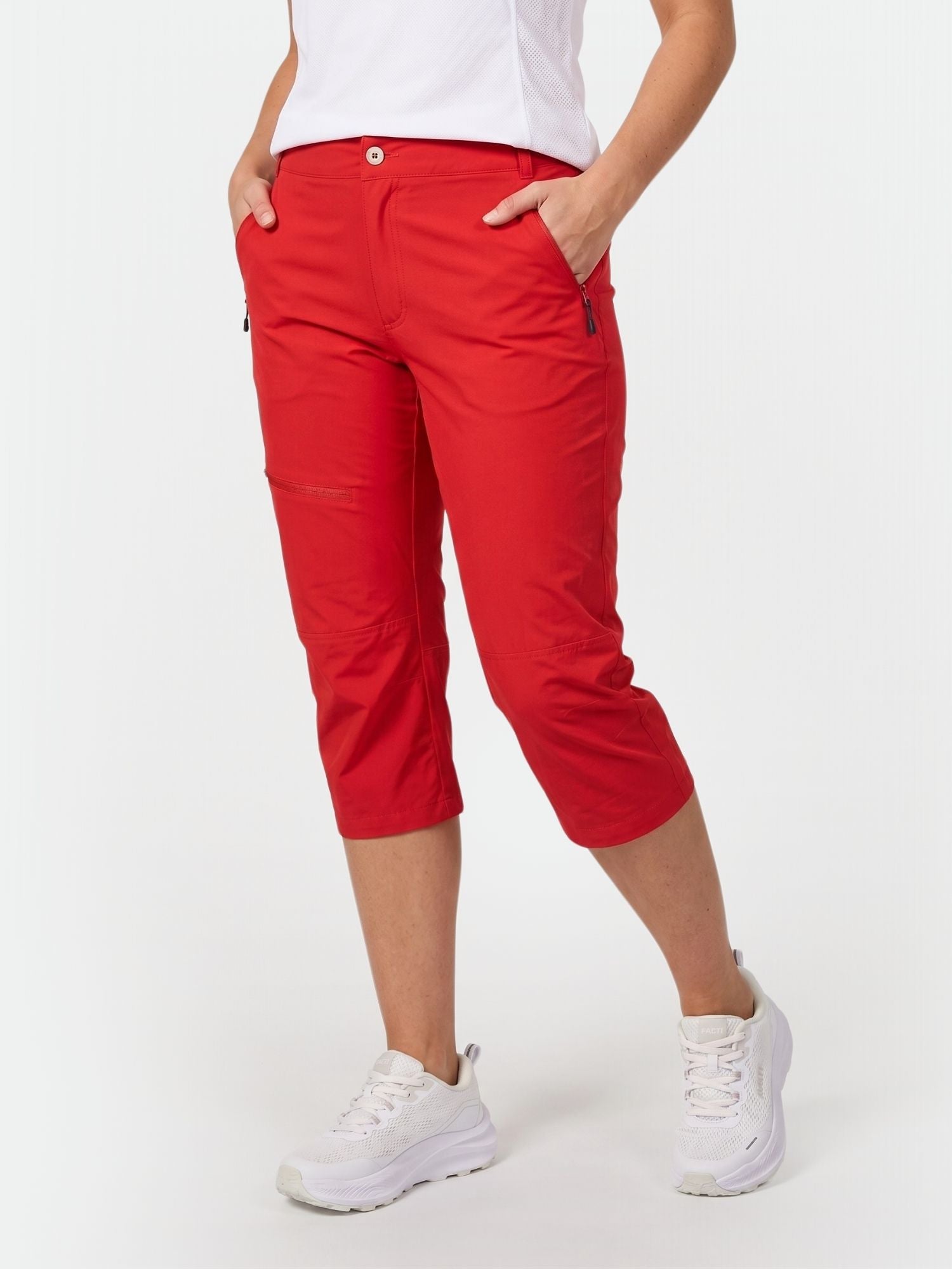 A person wears Halti Pallas Women's X-stretch Lite Capri pants, a white shirt, and sneakers with hands in pockets.