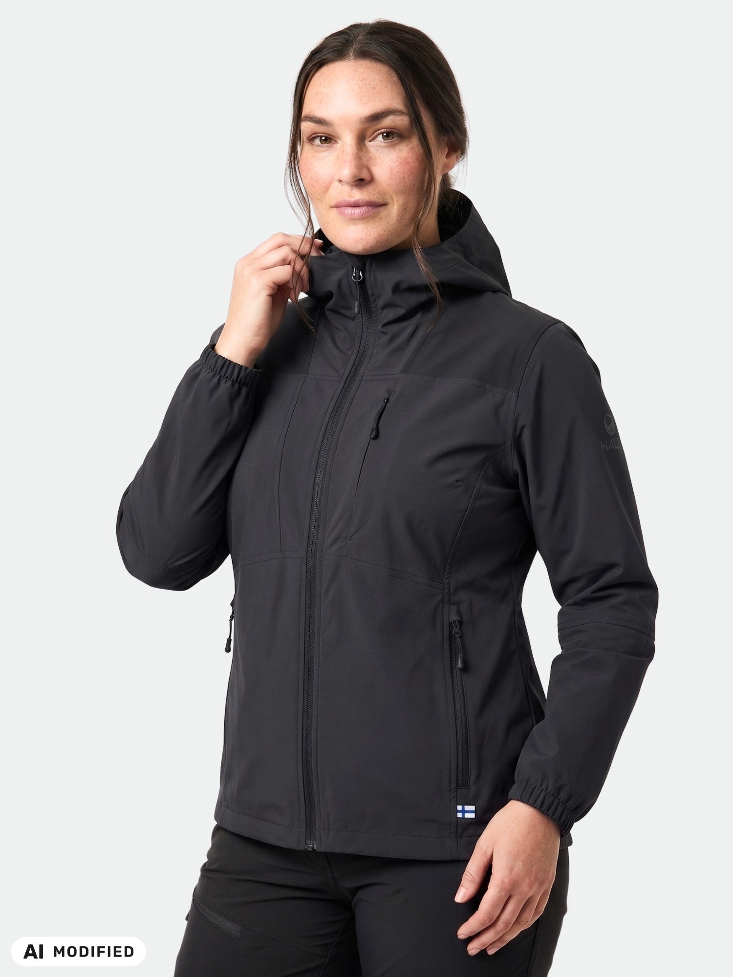 Woman in a Halti Pallas II X-stretch black jacket with zip pockets stands against a plain light background.