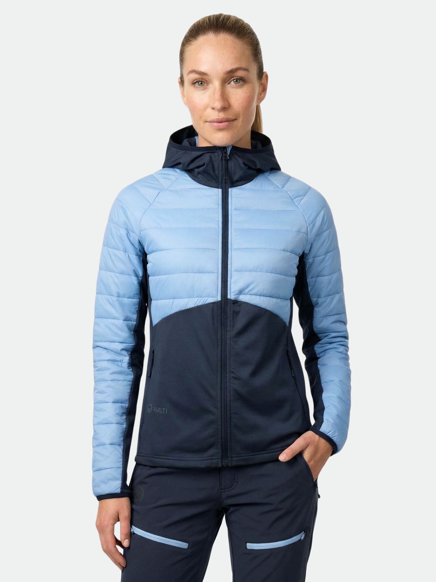 A woman faces forward in the Halti Veidnes Women's Insulation Jacket, paired with matching navy pants.