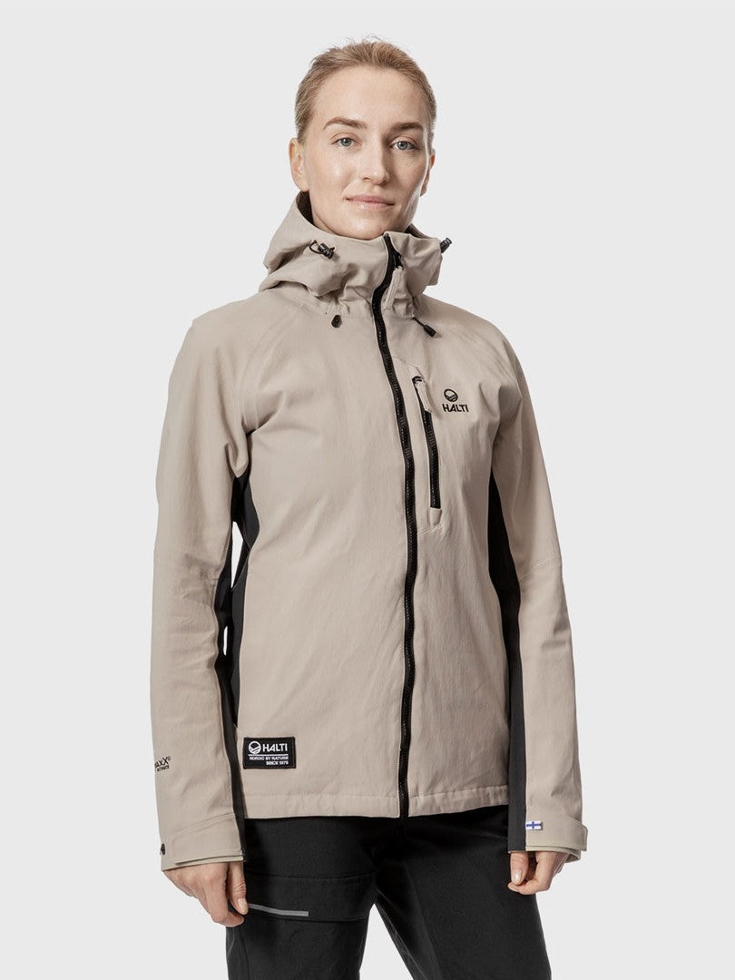 A woman wears the Halti Hiker Womens DrymaxX Pro Jacket in light beige with black accents, against a plain gray background.