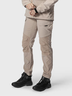 Woman stands against a plain background wearing Halti Hiker Womens Lite Outdoor Pants in beige and black shoes.