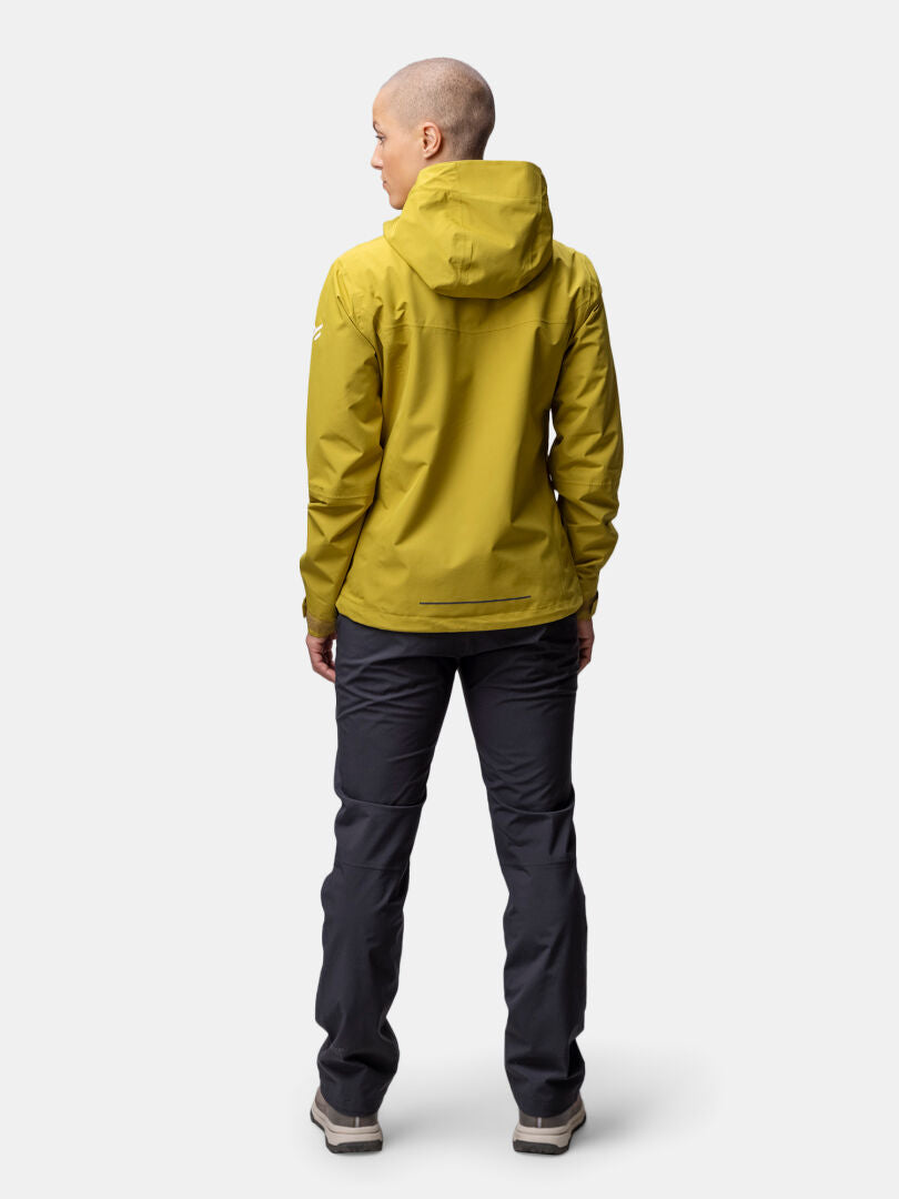 Woman facing away in a yellow Halti Forter DX Shell Jacket, perfect for hiking, with dark pants and light shoes.