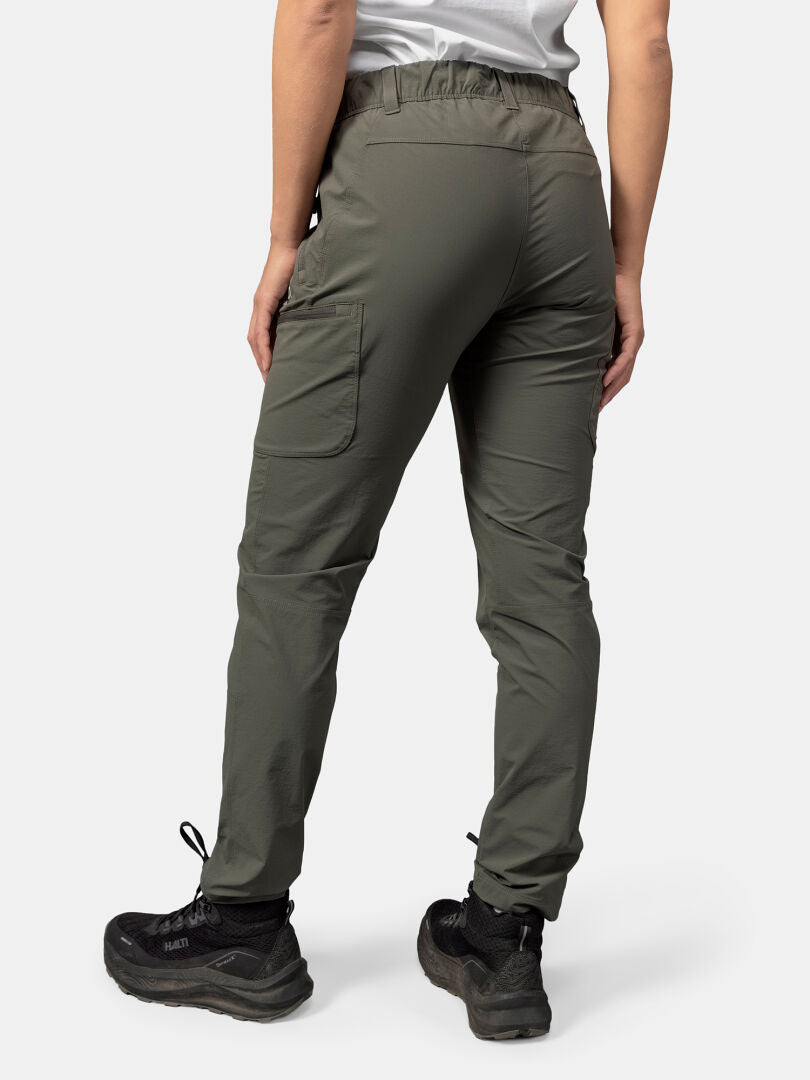 A person in Halti Pallas Evo X-stretch Pants Women's and black hiking shoes stands facing away against a plain background.