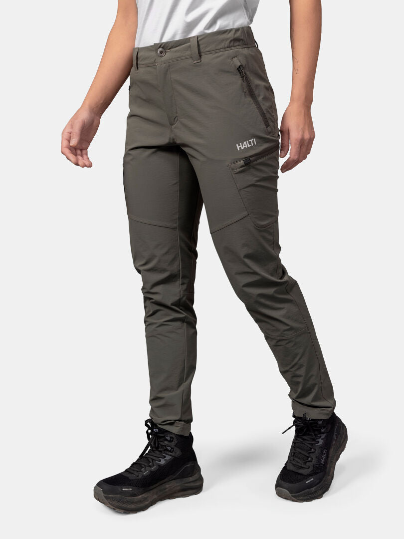 A person wears Halti Pallas Evo X-stretch Pants in olive green and black boots, standing on a white background.