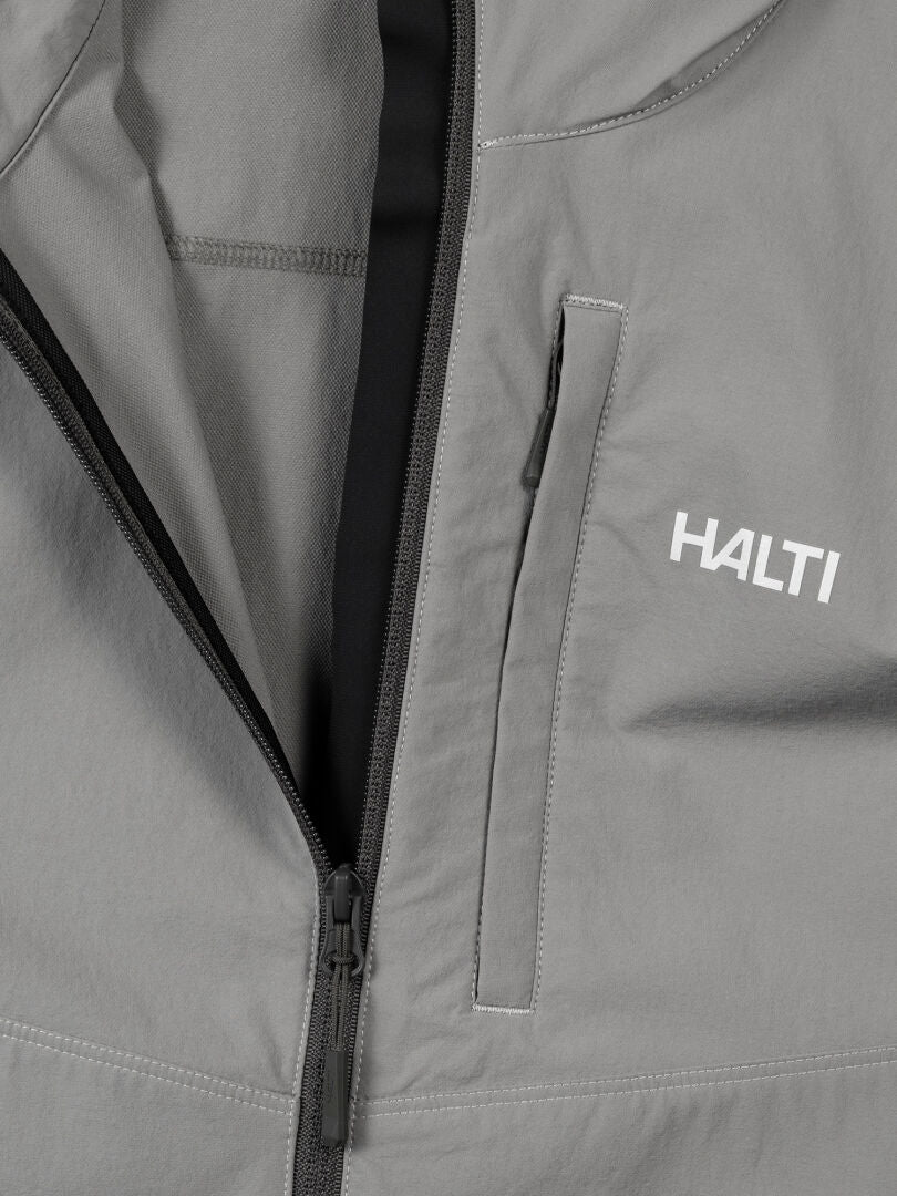 Close-up of the Halti Pallas Evo X-stretch men's jacket in gray with black zipper, chest pocket, and left-side logo.