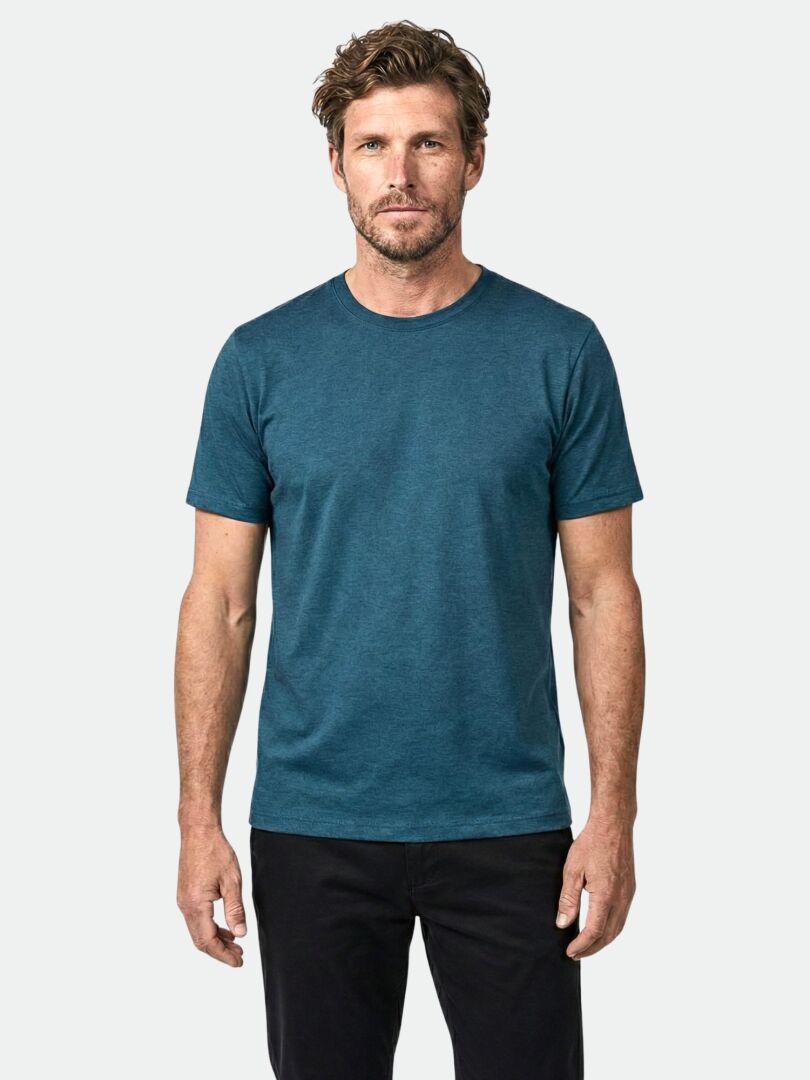 A man wears the Halti Tuntu II Merino T-shirt in teal with black pants against a plain background.