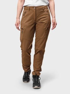 A person wears Halti Pallas Evo Brushed X-stretch Pants, a white shirt, and black hiking shoes against a plain background.
