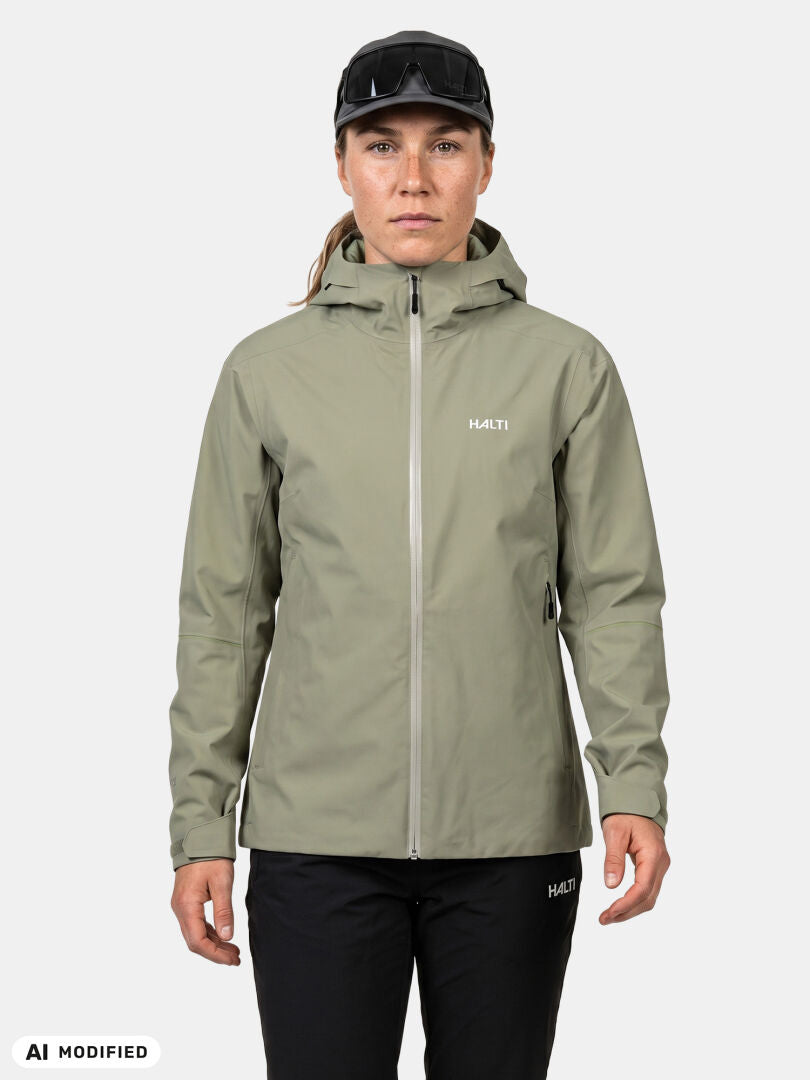 A person wears a light green Halti Staala DX Shell Jacket Women’s with black pants, standing against a white background.