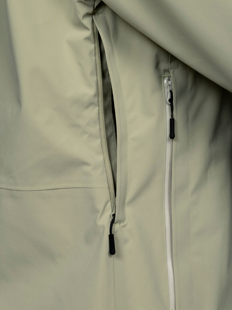 Close-up of a water-repellent Halti Staala DX Shell Jacket Women’s in light gray, showing two zippered pockets.