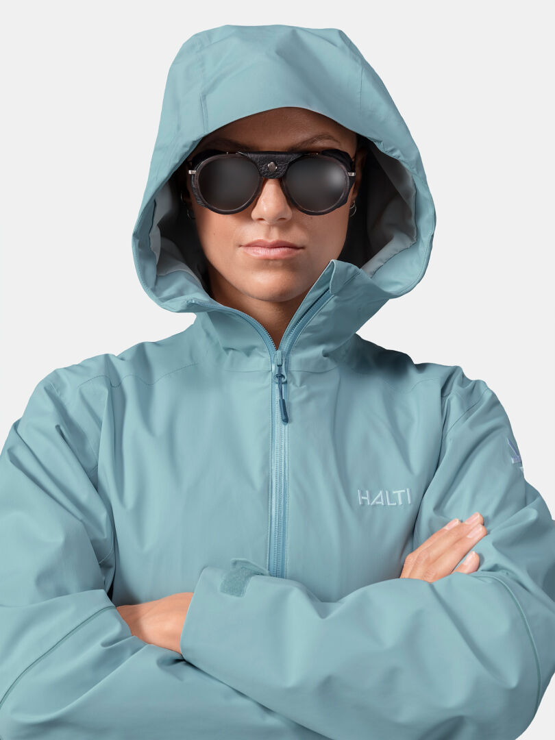 Woman in Halti Staala DX Shell Jacket and sunglasses, arms crossed, looking ahead.