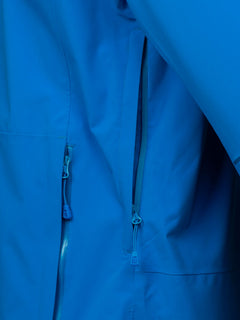 Close-up of Haltis Staala DrymaxX Shell Jacket Mens, a blue water-repellent technical jacket with zippered pockets.