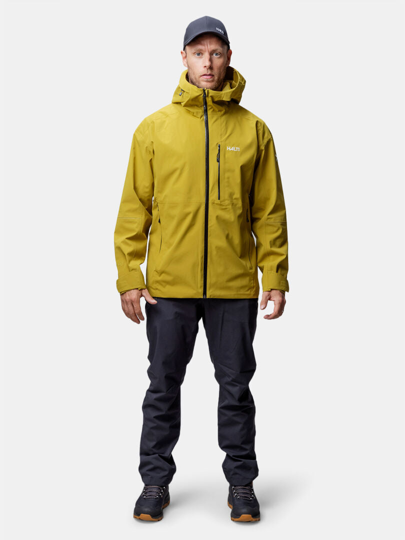 A man faces forward in a yellow Halti Staala DrymaxX Shell Jacket, paired with dark pants and shoes.