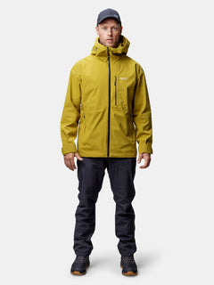 A man faces forward in a yellow Halti Staala DrymaxX Shell Jacket, paired with dark pants and shoes.
