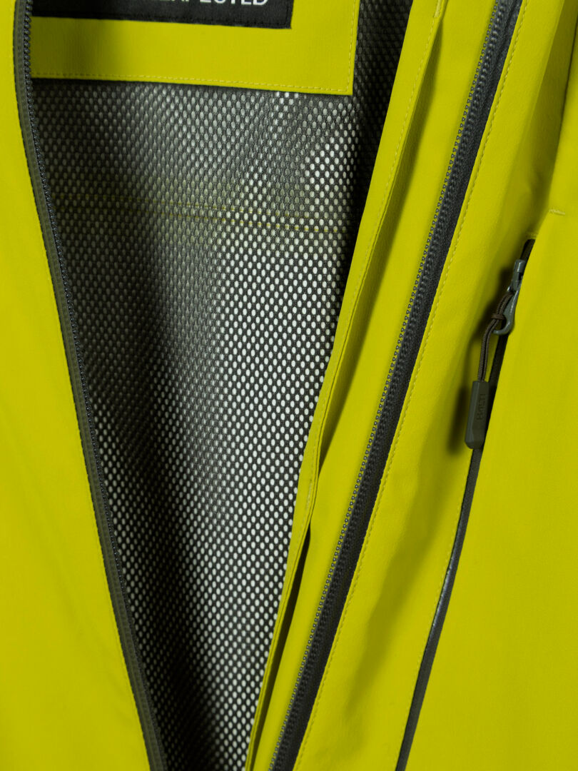 Close-up of Halti Staala DX Shell Jacket Men's in yellow, partly unzipped to show its black and white textured lining.