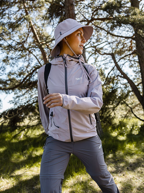A person wearing the Halti Pallas Cool X-stretch Jacket stands outdoors among trees in a forested area.