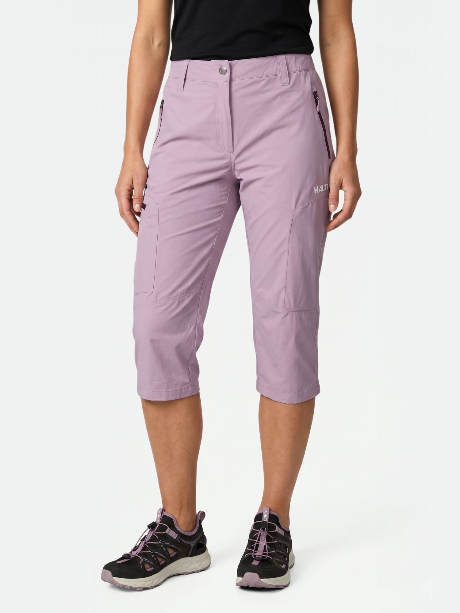 Model in Halti Pallas Cool X-stretch Capri Pants, black top, and black athletic shoes against a plain background.