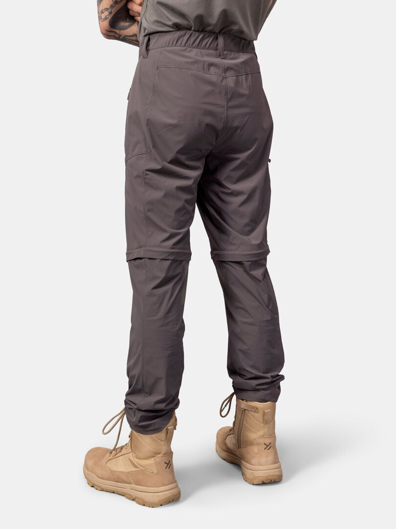 Man in gray Halti Pallas Cool Stretch Zip-off Pants and tan combat boots, shown from the back against a plain background.