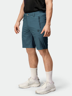 A person wears Halti Pallas Cool X-stretch Shorts in teal, a black shirt, white socks, and white sneakers.