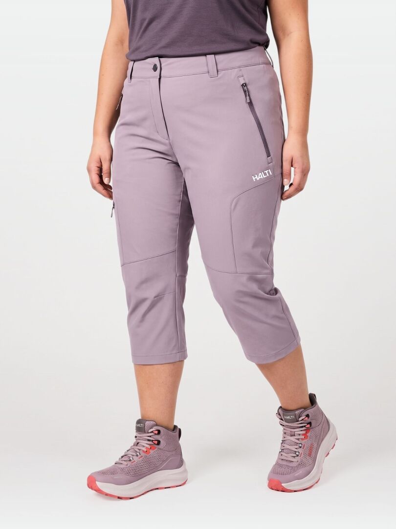 Person in Halti Pallas Cool X-stretch Capri Pants, a dark shirt, and light purple boots with pink soles, standing upright.
