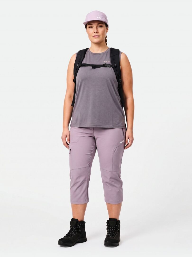 A person faces forward in a lilac cap, sleeveless top, Halti Pallas Cool X-stretch Women's Plus capris, boots, and backpack.