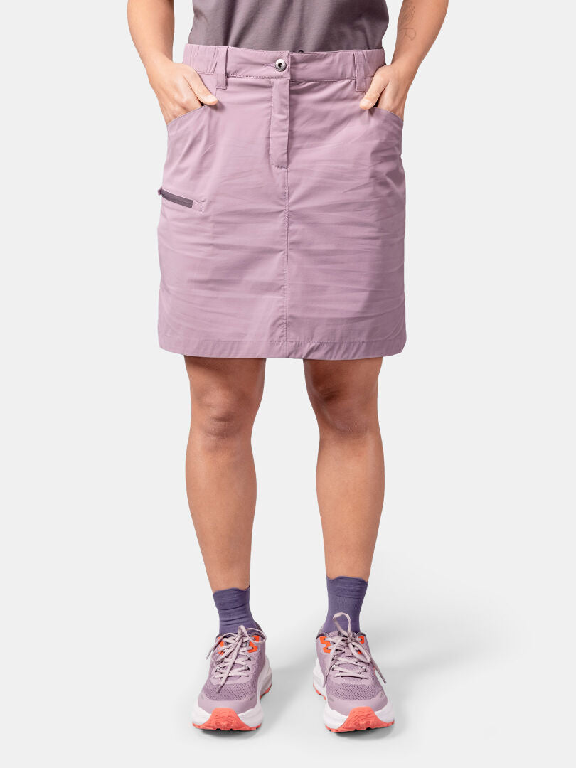 A woman in the Halti Pallas Cool Skort, hands in pockets, pairs it with purple socks and athletic shoes.