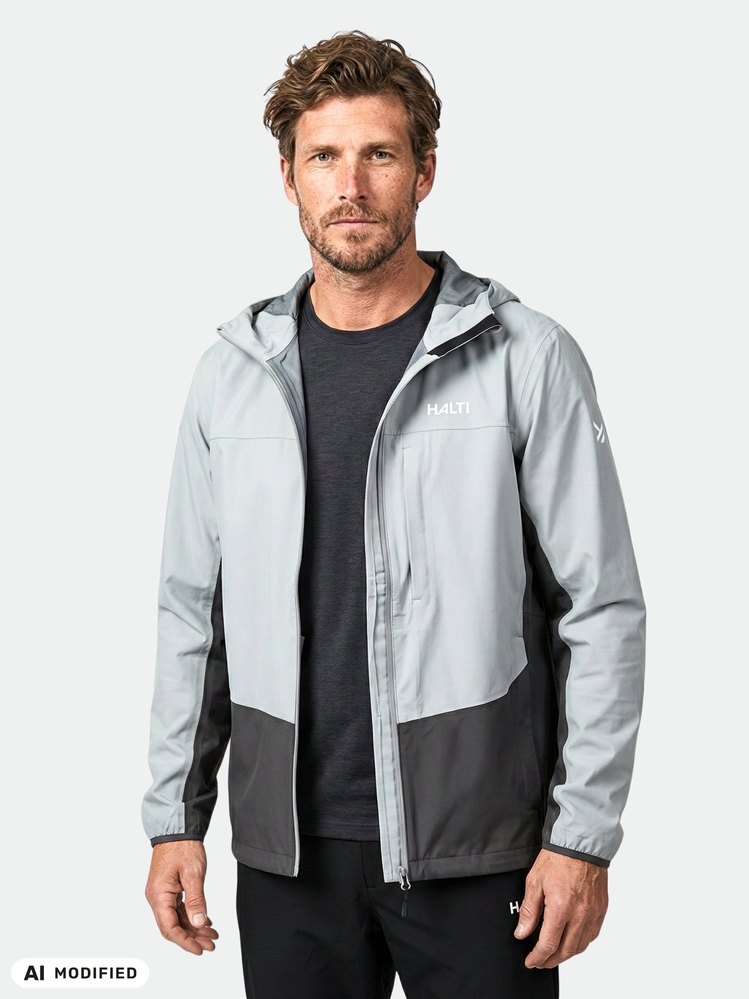 A man wears the Halti Taival DX 3L Jacket, light gray and black, with hood, against a white background.