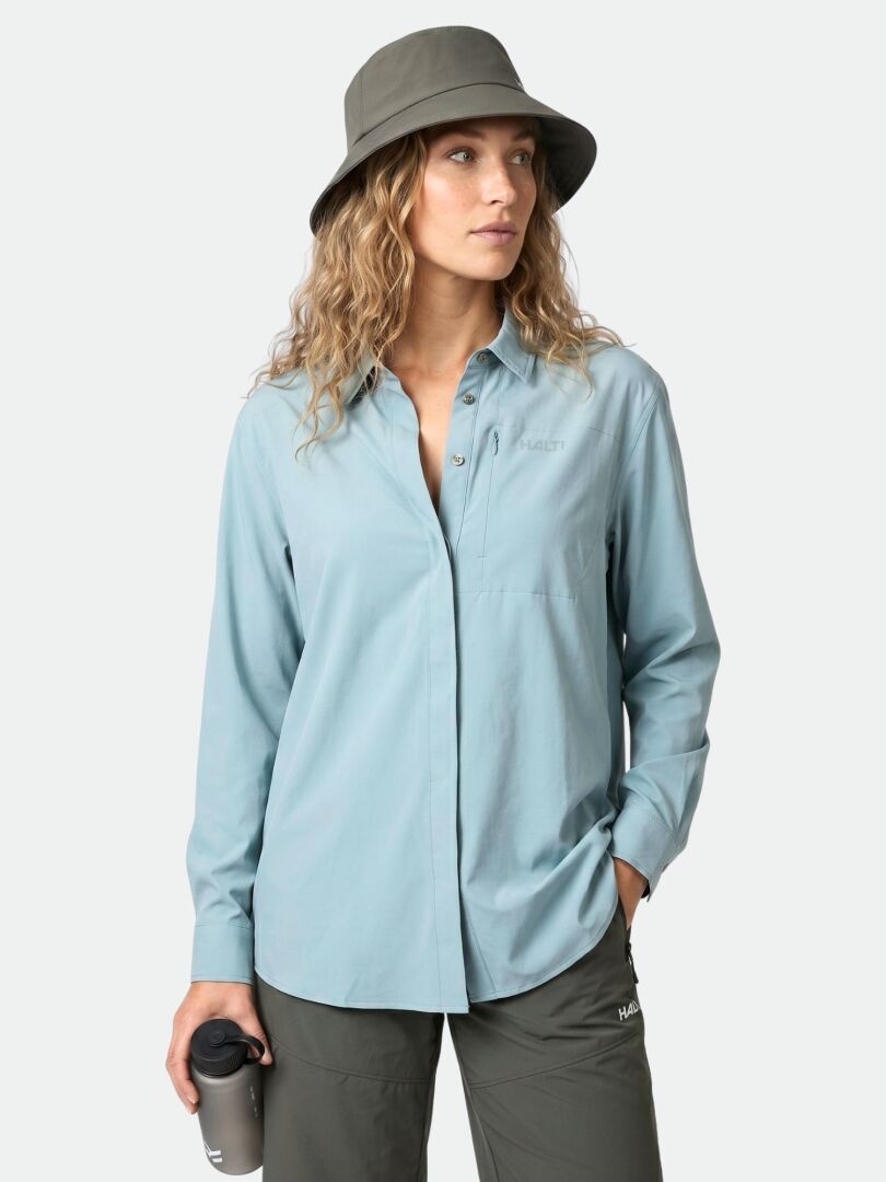 Woman wears the Halti Samoy Longsleeve Trekking Shirt, standing with one hand in her pocket against a plain background.