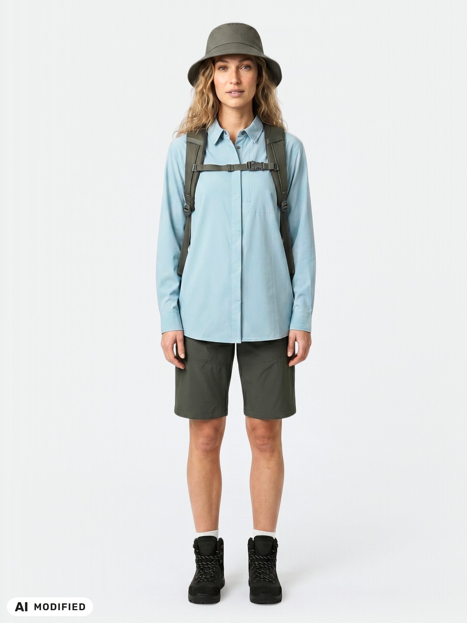 Woman wears Halti Samoy Longsleeve Trekking Shirt, dark shorts, boots, hat, and backpack.